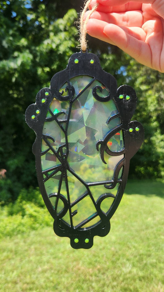 A rainbow suncatcher featuring spooky spirits around a cracked mirror outdoors against a green lawn background.